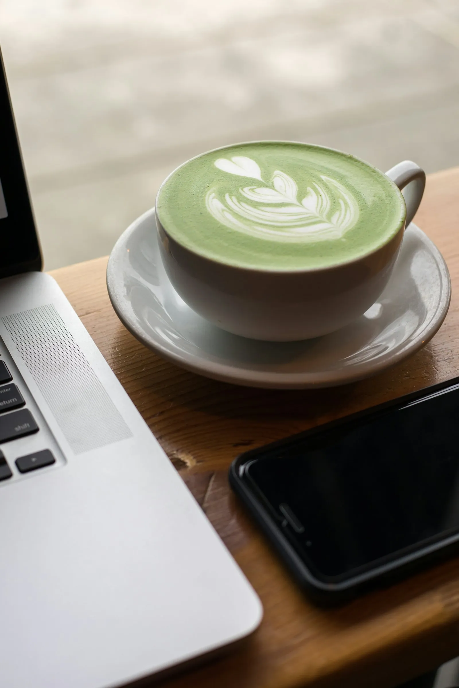 Matcha latte cu artă din lapte, lângă o fereastră luminoasă