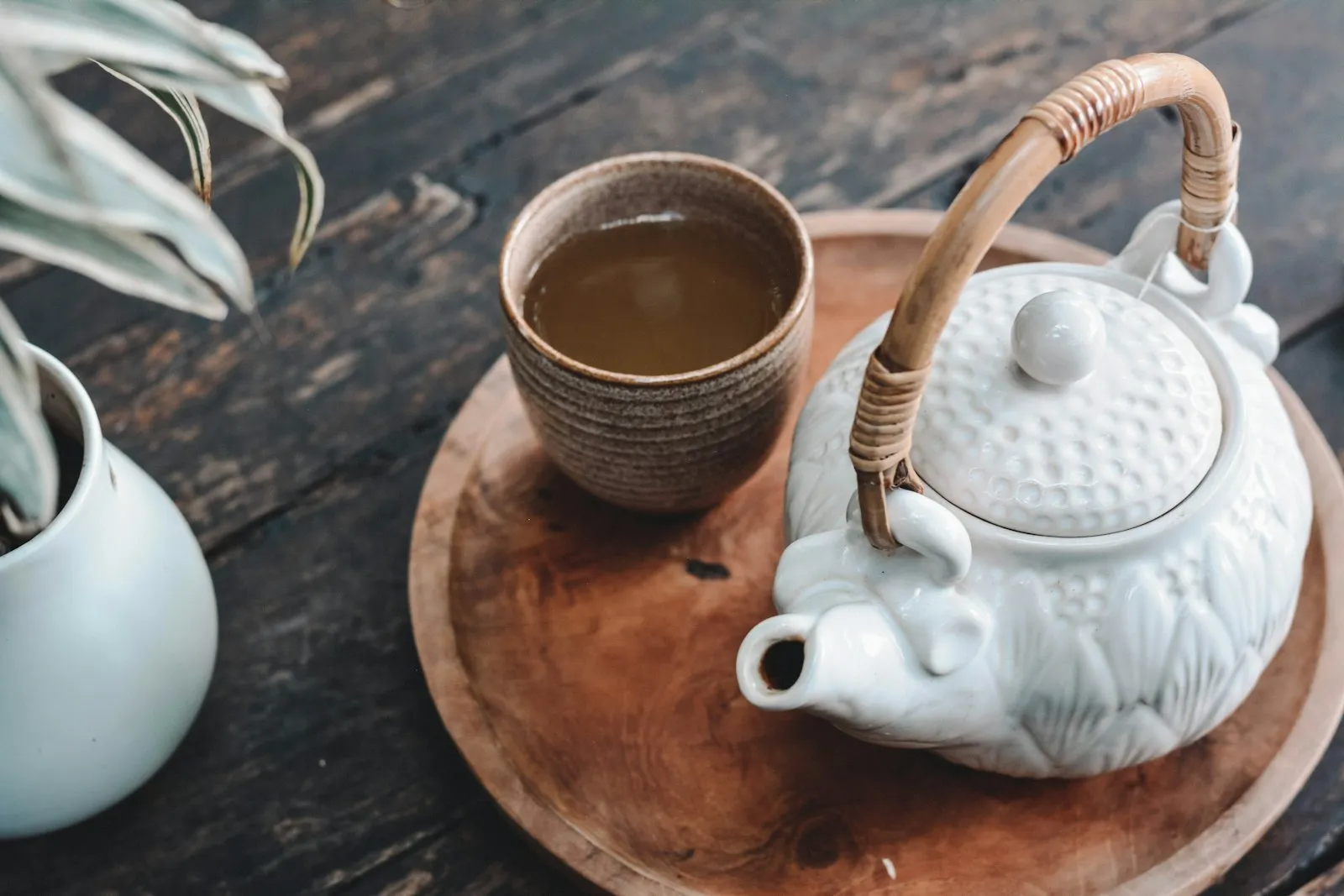 Ceainic alb și o ceașcă de ceai hojicha pe o tavă de lemn