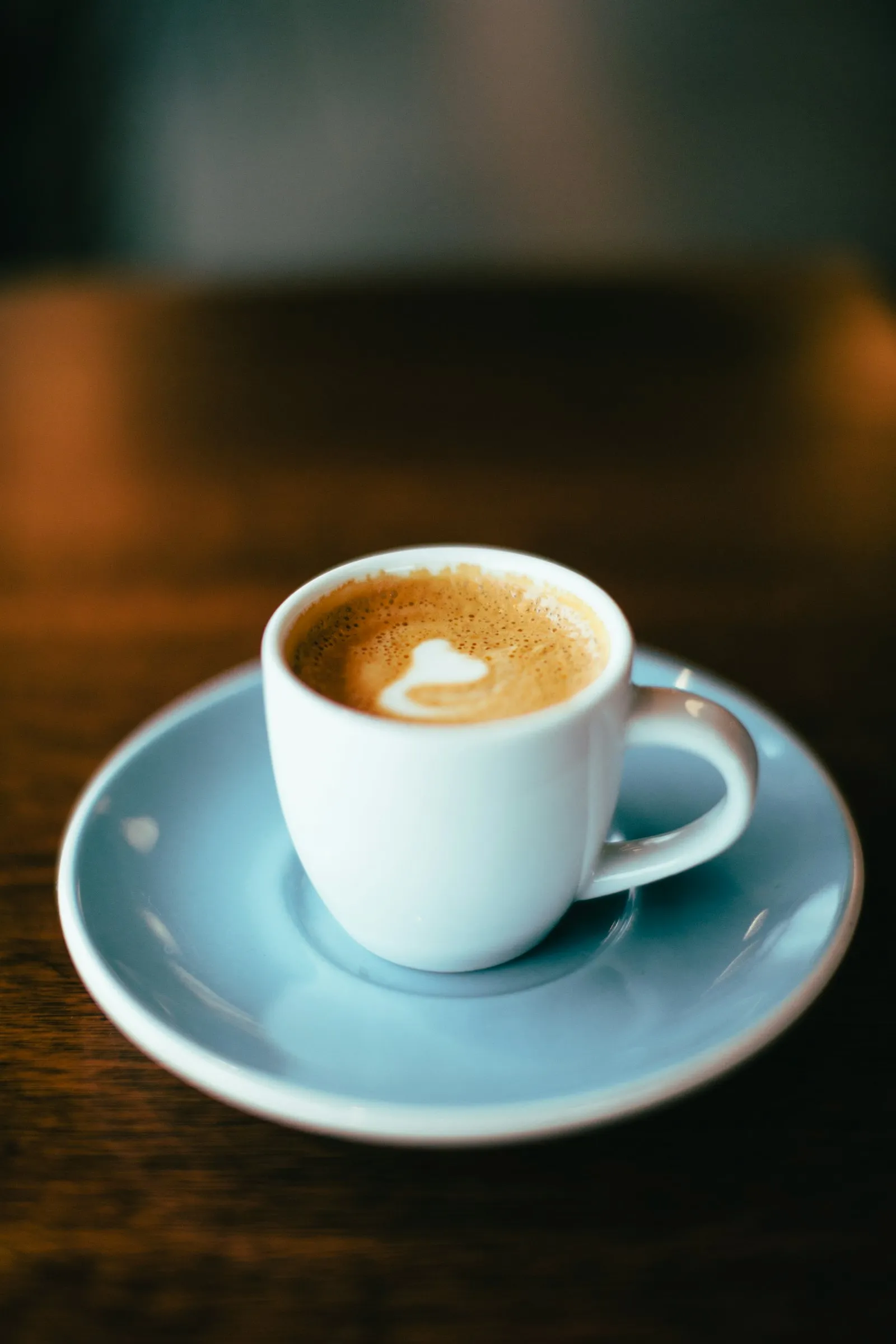 Ceașcă de cafea de specialitate KUMO pe o farfurioară albastră, în lumină calmă